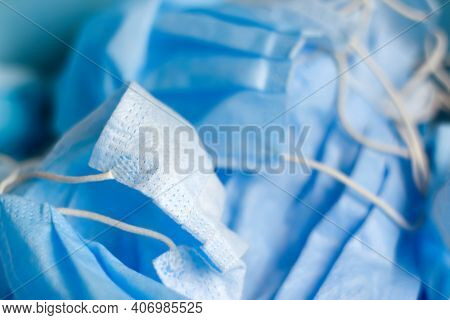 Defocus Close-up Protective Face Mask On Blur Blue Background. Medical Backdrop. Many Surgical Masc.