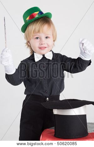 Magician - little boy in a green hat waved his wand over the hat