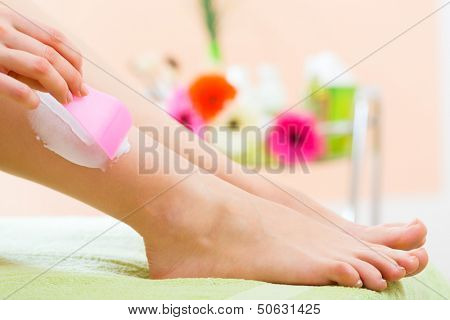 Young woman in Spa getting legs creamed for hair removal