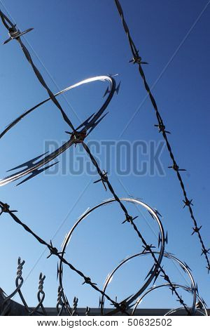 Large metal fence with barbwire and razor wire