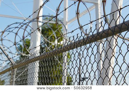 Large metal fence with barbwire and razor wire