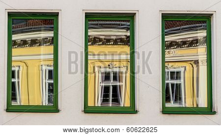 a renovated house reflected in modern windows of an office building