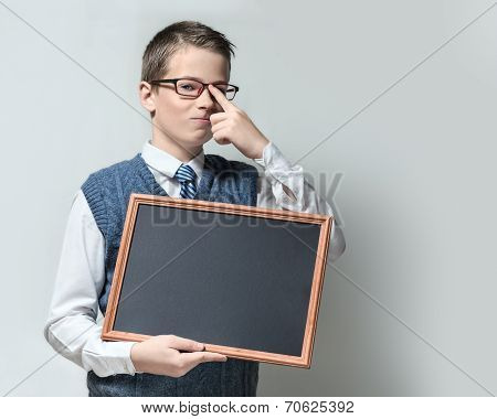 Smart schoolboy in glasses with empty chalkboard
