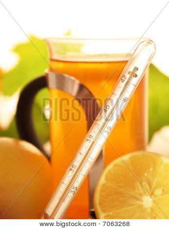 Termometer med te og citron i baggrunden