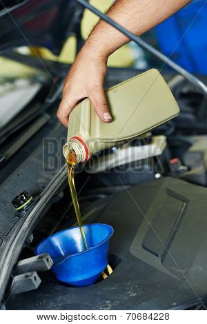 auto mechanic technician replacing and pouring motor oil into automobile engine at maintenance repair service station