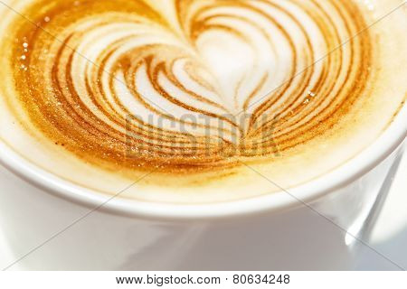 Cappuchino or latte coffe in a white cup with heart shaped foam