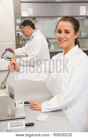 Pharmacist using press to make pills at the laboratory