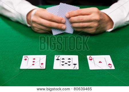 casino, gambling, poker, people and entertainment concept - close up of poker player holding playing cards at green casino table