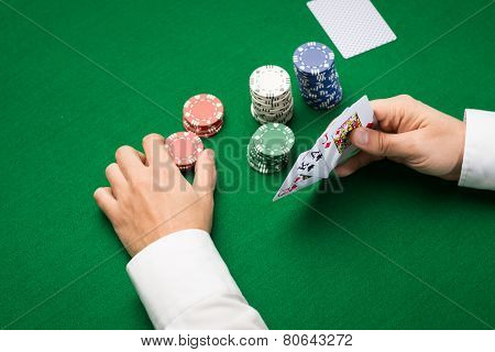 casino, gambling, poker, people and entertainment concept - close up of poker player with playing cards and chips at green casino table