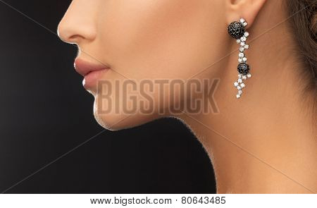 beauty and jewelery concept - woman wearing shiny diamond earrings