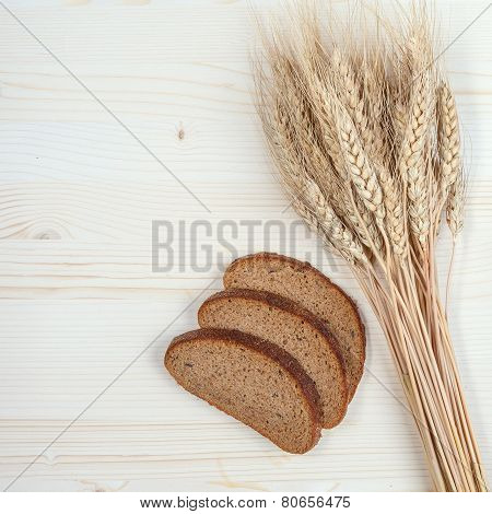Rustic bread and wheat on an old planked wood table