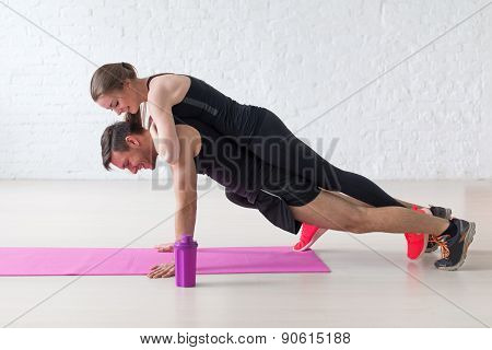 man doing push ups with woman laying on back at gym or home concept fitness sport training teamwork
