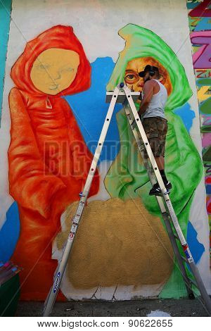 Street artist Bob Plater painting mural at JMZ Walls in Brooklyn