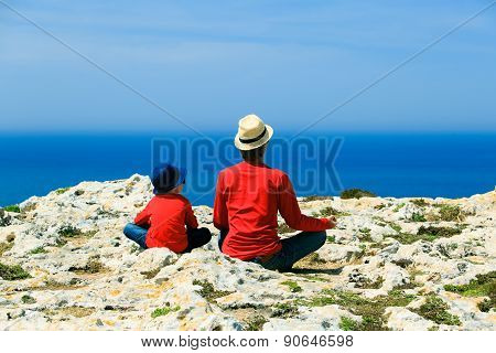 father and son doing yoga in mountains