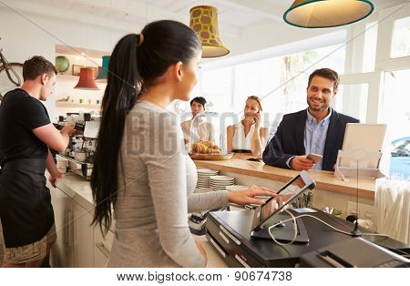 Young man ordering at the counter in a cafe