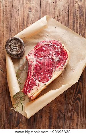 raw beef Rib bone  steak  on paper  and table with 2lb iron weight
