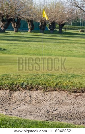 Yellow Flagstick In Golf Course In Sunny Day