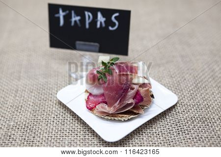 Fresh delicious Spanish tapas with hamon with fresh herbs and strawberries with poster TAPAS on the  wooden background . Great background for restaurant, cafe.