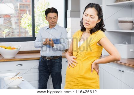 Pregnant woman with back ache in the ktichen