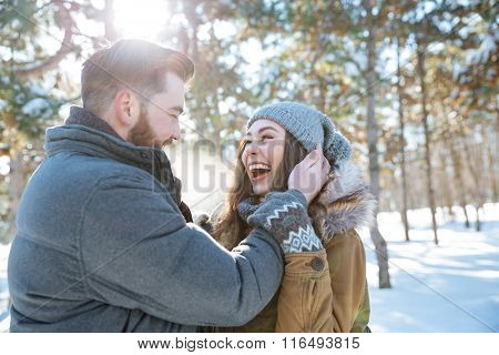 Cheerful young couple standing together in winter park