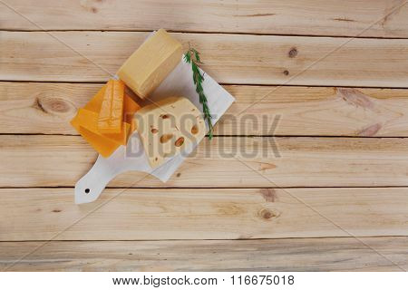 various types of fresh raw aged delicatessen cheese on white plate over light wooden table cheddar edam swiss