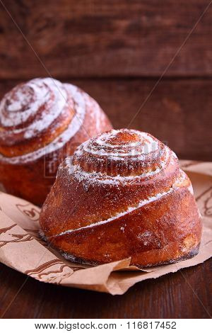 Buns With Cinnamon And Powdered Sugar On A Dark Wooden Background