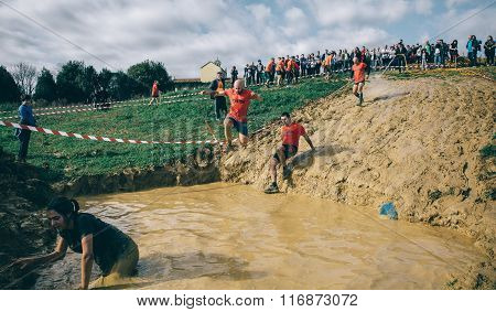 Runner jumping to mud pit in a test of extreme obstacle race