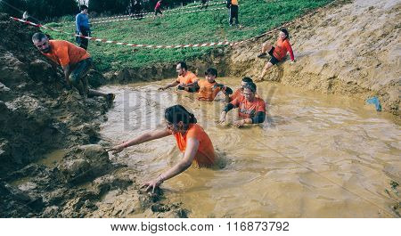 Runners crossing mud pit in a test of extreme obstacle race