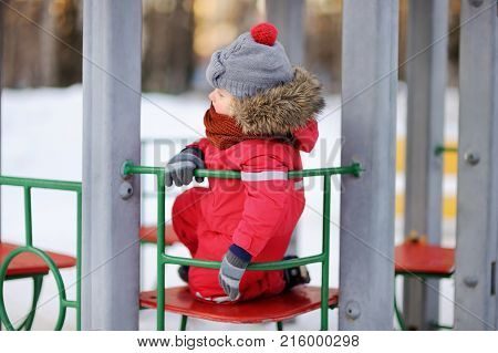 Little Boy In Red Winter Clothes Having Fun On Outdoor Playground
