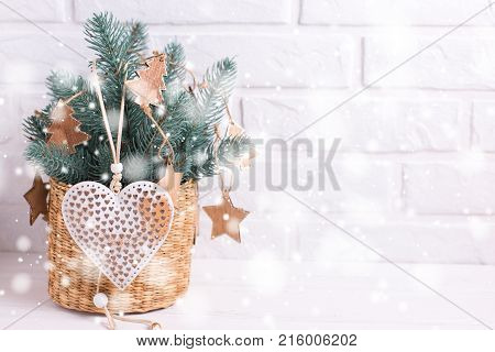 Christmas toys heart and branches fur tree on white wooden background. Decorative christmas composition. Selective focus. Place for text. Drawn snow effect.