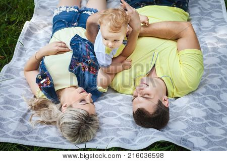 beautiful young family resting in city park, cute couple playing with his little baby, concept happy family