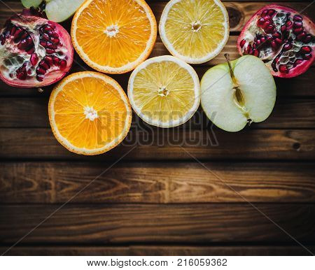 Fresh fruits on wooden background. Orange apple lemon pomegranate.