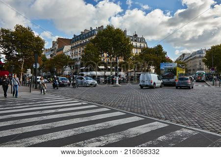 Paris, France - October 3 2017: Pedestrians passing pedestrian crossing and cars standing in traffic on Place de l'Ecole Militaire at morning time.