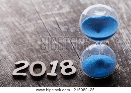 New year 2018 time concept. Hourglass or sandglass on rustic wooden table.
