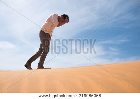 Man walking alone in the sunny desert. He is lost and out of breath. No water and energy. Concept for depression and noway situation in life