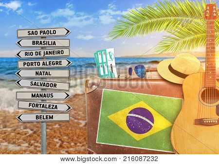 Concept of summer traveling with old suitcase and Brazil town sign with burning sun