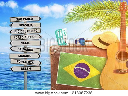 Concept of summer traveling with old suitcase and Brazil town sign with burning sun