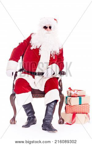 Portrait of swaggy Santa Claus in sunglasses relaxing in chair on white background