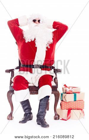 Portrait of swaggy Santa Claus in sunglasses relaxing in chair on white background