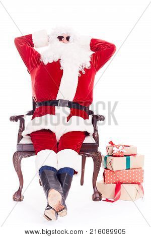 Portrait of swaggy Santa Claus in sunglasses relaxing in chair on white background