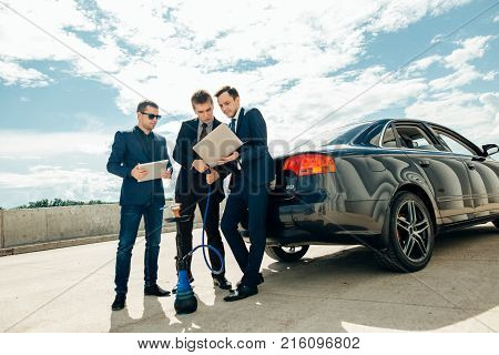 three Businessman Using Digital Tablet Outside against car.