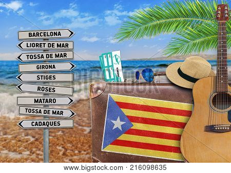 Concept of summer traveling with old suitcase and Catalonia town sign