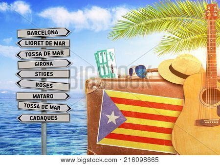 Concept of summer traveling with old suitcase and Catalonia town sign with burning sun