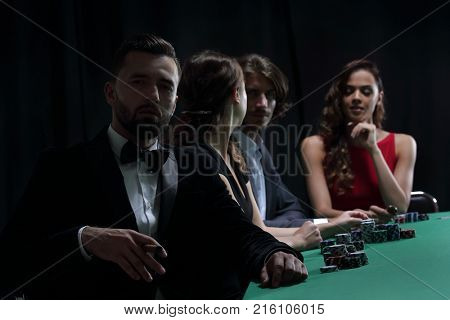 Man with cigar looking up from poker game in casino