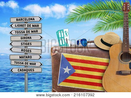 Concept of summer traveling with old suitcase and Catalonia town sign