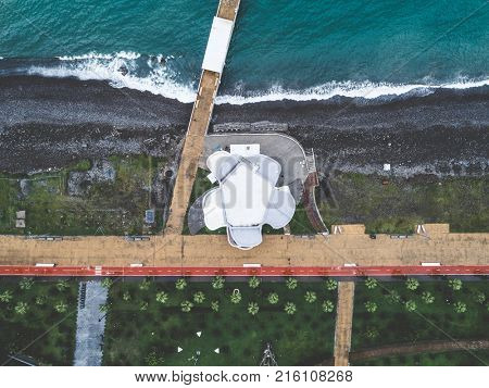 Aerial view of desrted embankment with modern building, banquette and greeen park. Batumi, Georgia. Top view.