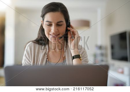 Home-office teleoperator talking on phone with headset