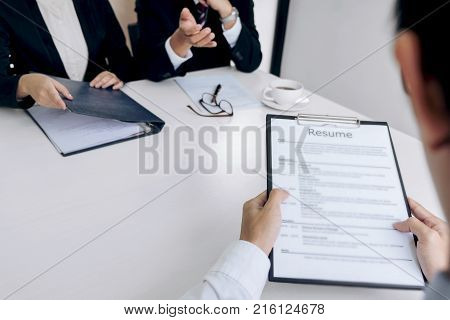 Interviewer or Board reading a resume during a job interview Employer interviewing a young male job seeker for recruitment talking in modern office employment and recruitment concept.