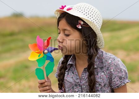 Smiling girl with strawhat and pinwheel. Outdoor Shot.