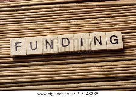 Word FUNDING written on wooden cubes. Finance concept